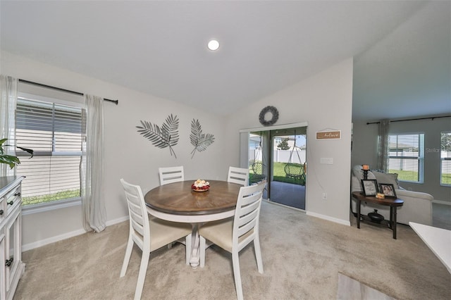 carpeted dining space featuring a wealth of natural light and lofted ceiling