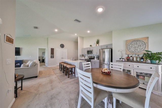 carpeted dining space featuring lofted ceiling and sink