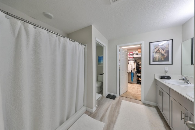 bathroom featuring vanity, a shower with shower curtain, a textured ceiling, and toilet