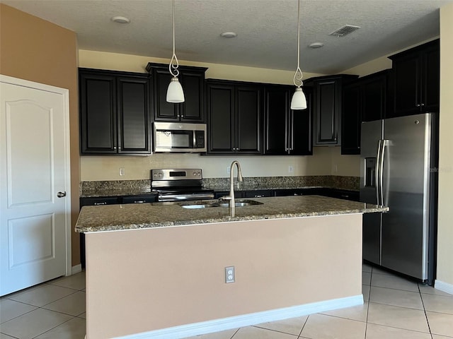 kitchen with sink, an island with sink, hanging light fixtures, and appliances with stainless steel finishes