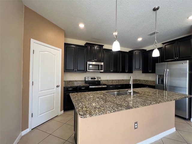 kitchen with sink, a kitchen island with sink, stainless steel appliances, and pendant lighting