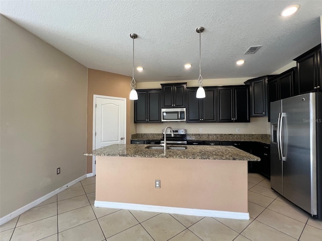 kitchen with sink, a center island with sink, hanging light fixtures, and appliances with stainless steel finishes