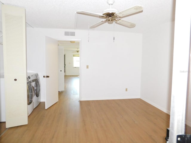 laundry area with washer and clothes dryer, a textured ceiling, and light wood-type flooring