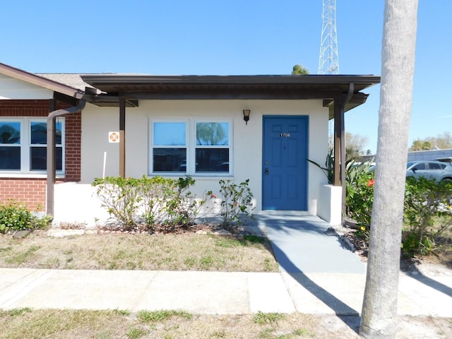 doorway to property with brick siding and stucco siding