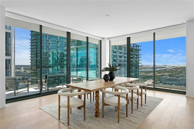 dining area with expansive windows, light hardwood / wood-style floors, and plenty of natural light