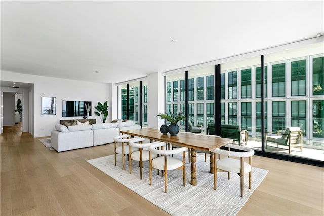 dining area featuring a wall of windows and light hardwood / wood-style floors