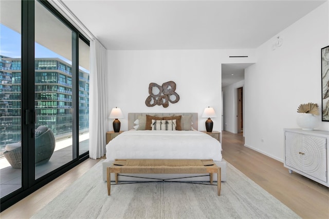 bedroom featuring access to outside, floor to ceiling windows, and light wood-type flooring