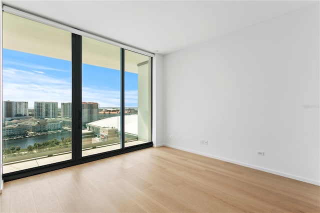 spare room with a water view, floor to ceiling windows, and light hardwood / wood-style flooring