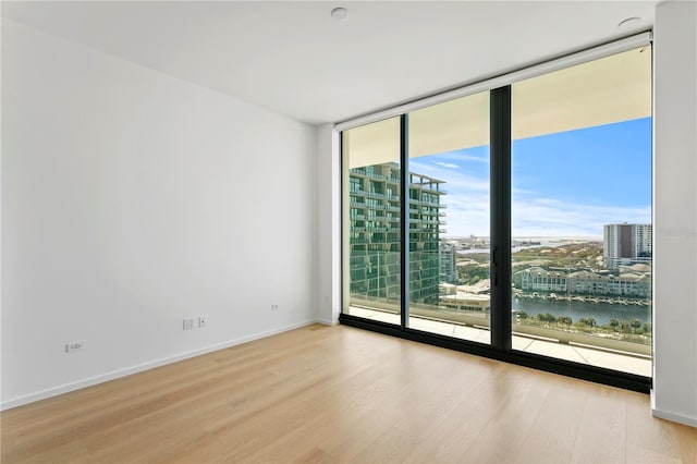 1000 Water St Unit 1402, Tampa, FL 33602 - spare room with expansive windows, wood finished floors, a city view, and baseboards