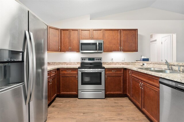 kitchen featuring sink, vaulted ceiling, appliances with stainless steel finishes, and light hardwood / wood-style flooring