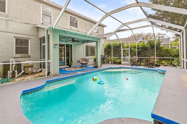 view of swimming pool featuring ceiling fan, a patio area, and glass enclosure