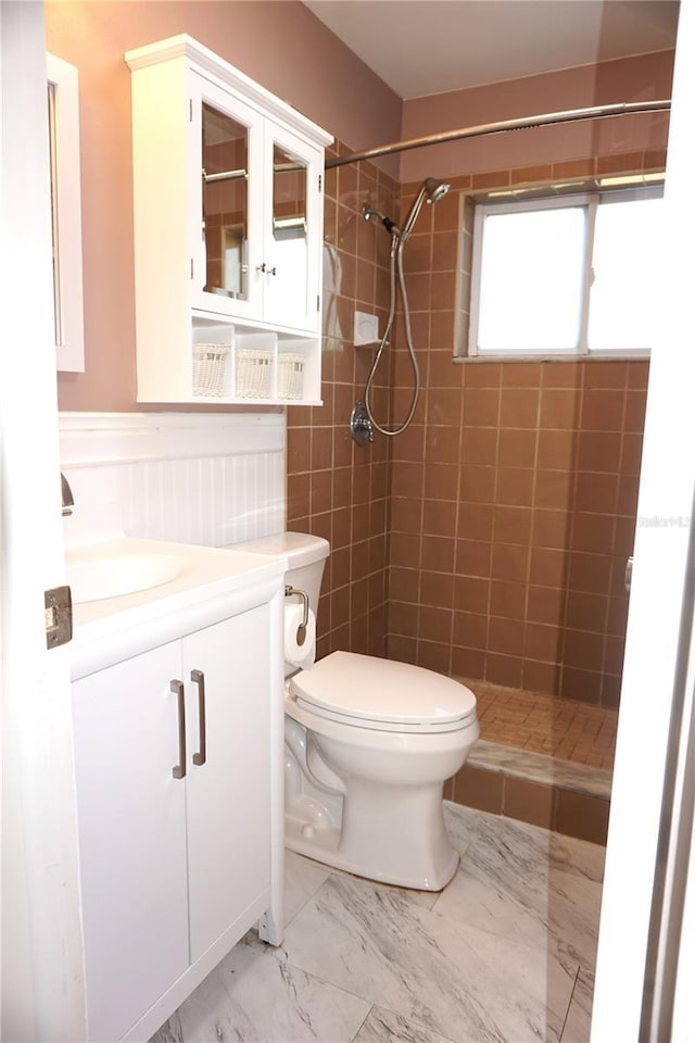 bathroom with vanity, toilet, and tiled shower