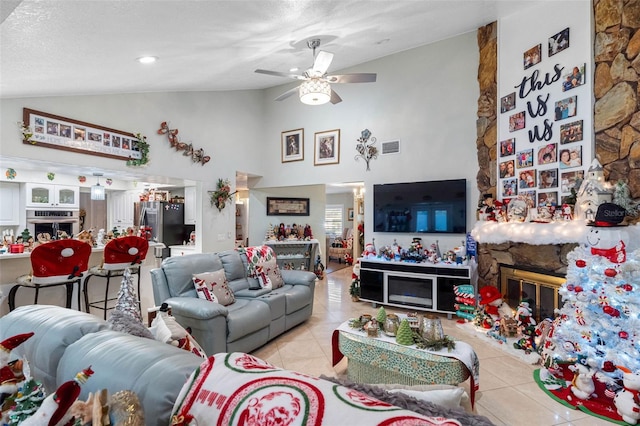 living room with ceiling fan, a fireplace, light tile patterned floors, and a textured ceiling