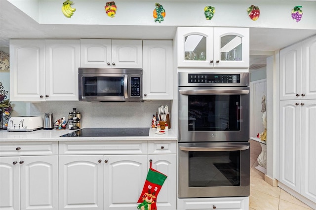 kitchen with white cabinets, light tile patterned floors, stainless steel appliances, and tasteful backsplash