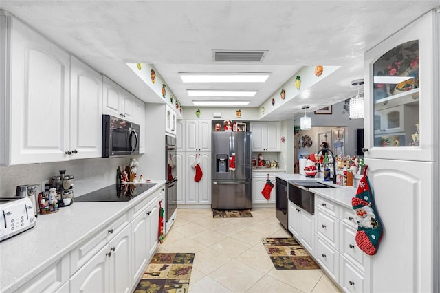 kitchen featuring white cabinetry, light tile patterned floors, decorative light fixtures, and appliances with stainless steel finishes