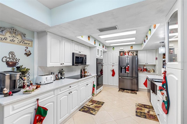 kitchen with white cabinets, light tile patterned floors, pendant lighting, and black appliances