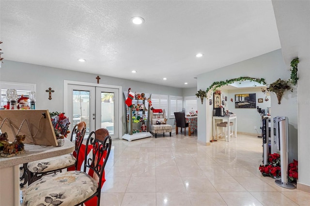 tiled living room featuring french doors and a textured ceiling