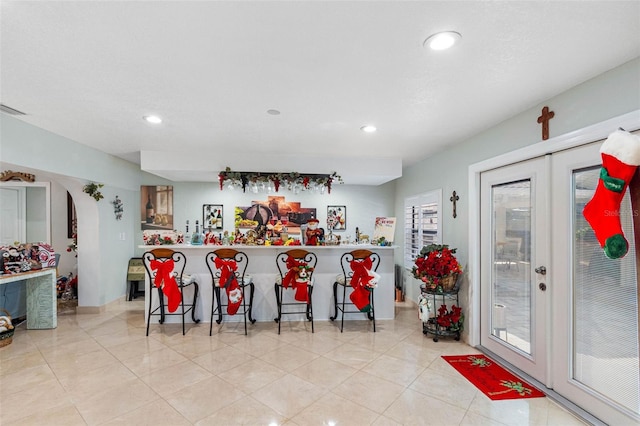 kitchen with kitchen peninsula, french doors, light tile patterned floors, and a breakfast bar