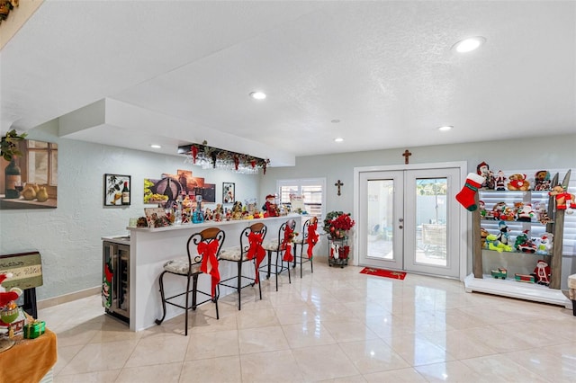 kitchen with french doors, a textured ceiling, light tile patterned floors, and a breakfast bar area