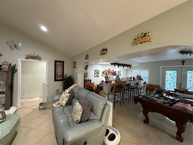 living room with french doors, light tile patterned floors, vaulted ceiling, a textured ceiling, and a bar