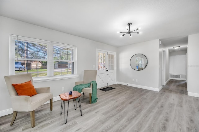 sitting room with a notable chandelier and light hardwood / wood-style floors