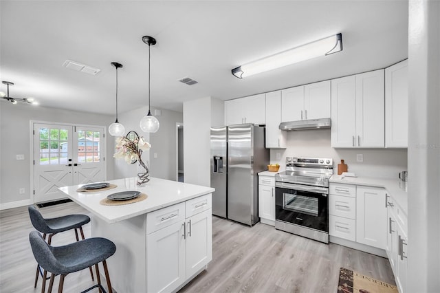 kitchen with appliances with stainless steel finishes, pendant lighting, and white cabinets