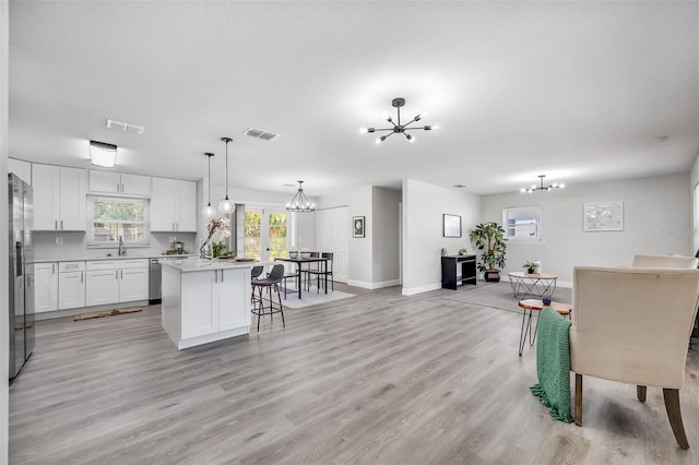 kitchen featuring light hardwood / wood-style flooring, a center island, decorative light fixtures, and white cabinets