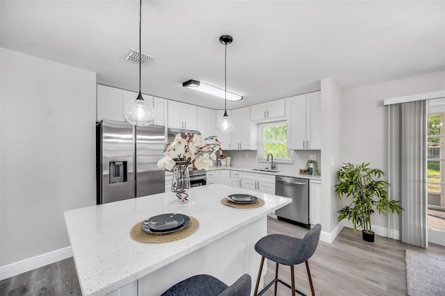 kitchen with a center island, white cabinets, stainless steel appliances, and plenty of natural light