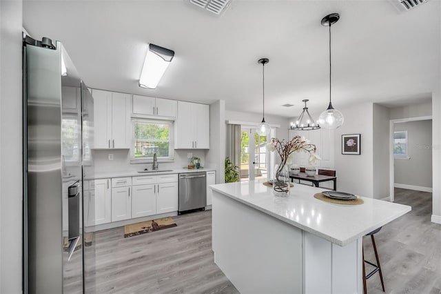 kitchen featuring appliances with stainless steel finishes, pendant lighting, a kitchen island, and white cabinets