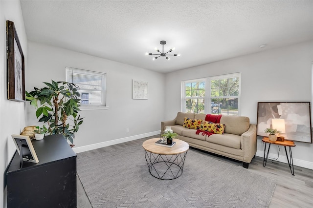 living room featuring a notable chandelier, a textured ceiling, and light hardwood / wood-style flooring