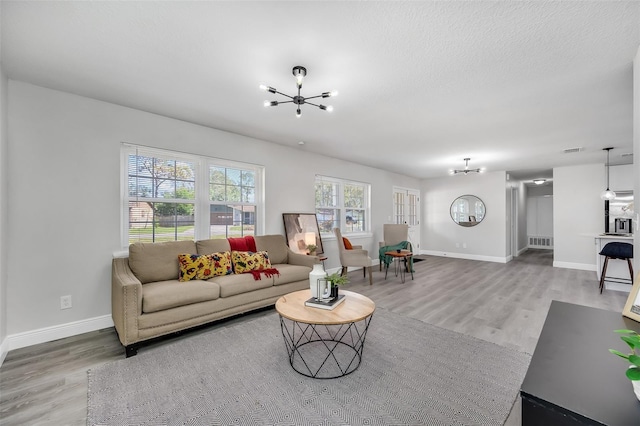 living room featuring a textured ceiling, hardwood / wood-style flooring, and an inviting chandelier