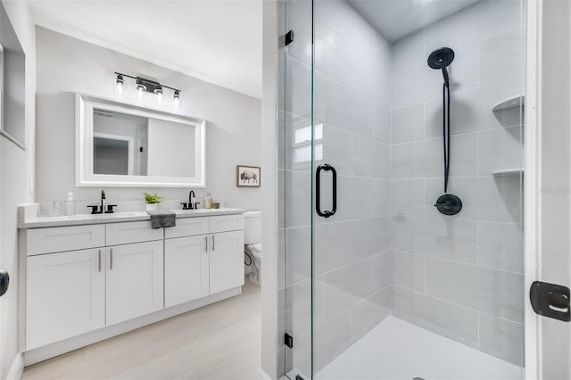 bathroom featuring toilet, an enclosed shower, and vanity