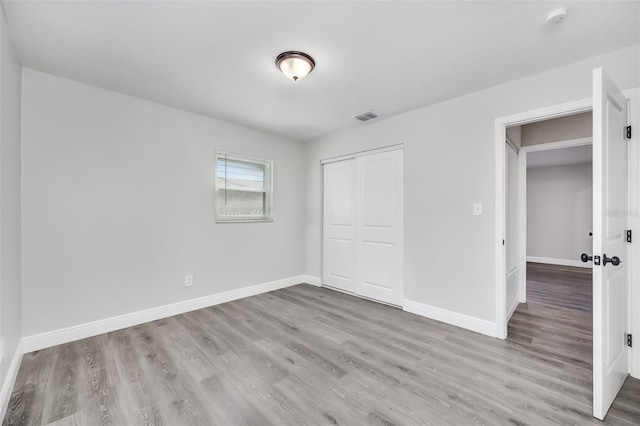 unfurnished bedroom featuring light hardwood / wood-style flooring and a closet