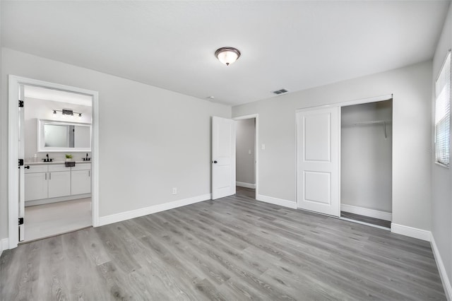 unfurnished bedroom featuring a closet, light hardwood / wood-style flooring, and ensuite bathroom