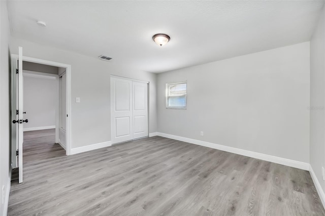 unfurnished bedroom with a closet and light wood-type flooring