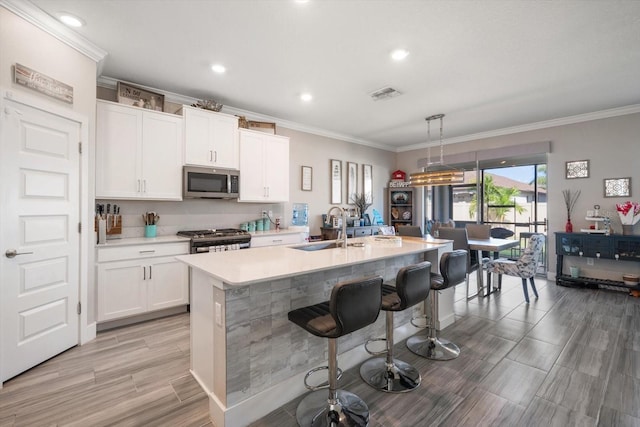 kitchen featuring sink, white cabinetry, stainless steel appliances, and an island with sink