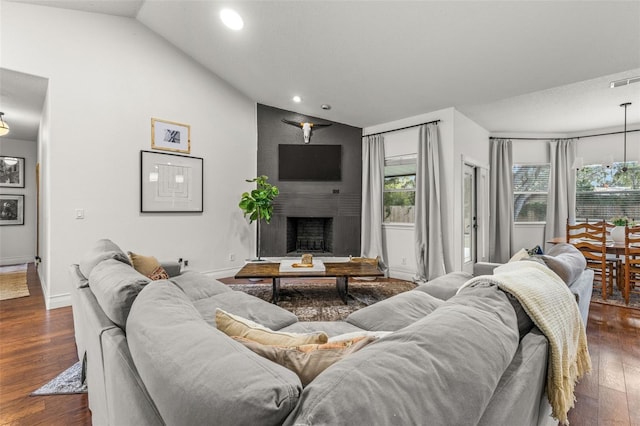 living room featuring dark wood-type flooring, a fireplace, and vaulted ceiling