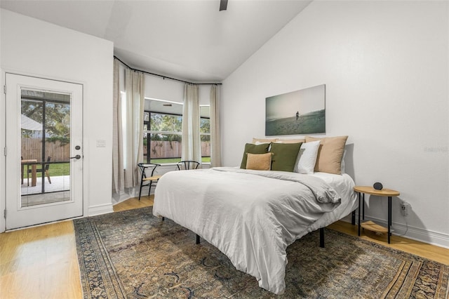 bedroom with hardwood / wood-style floors, vaulted ceiling, access to outside, and ceiling fan