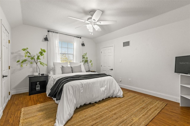 bedroom with a textured ceiling, ceiling fan, wood-type flooring, and vaulted ceiling