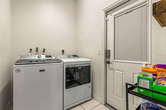 laundry room featuring washing machine and clothes dryer and light tile patterned floors