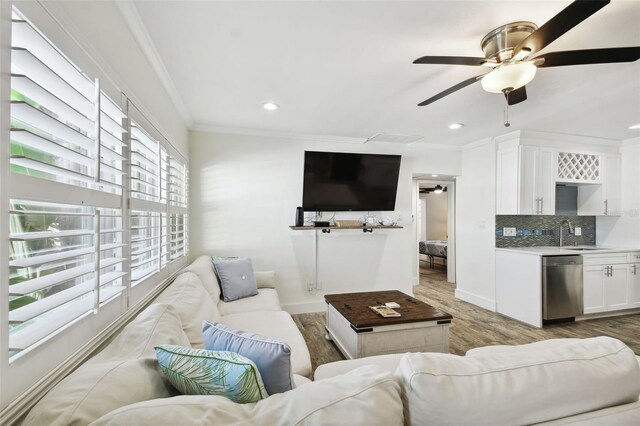 living room featuring crown molding, light wood finished floors, ceiling fan, baseboards, and recessed lighting