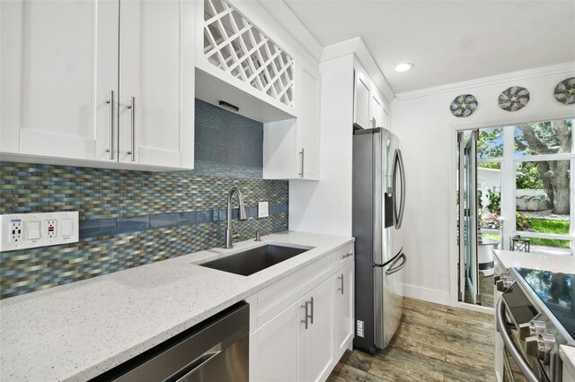 kitchen featuring stainless steel appliances, a sink, light stone countertops, backsplash, and white cabinets