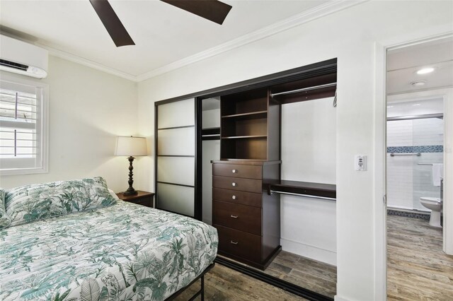 bedroom featuring a wall mounted AC, wood finished floors, ornamental molding, ceiling fan, and baseboards