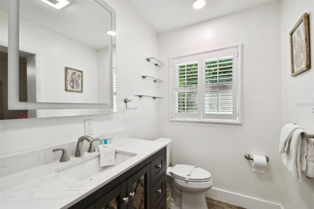 half bath featuring toilet, vanity, and recessed lighting