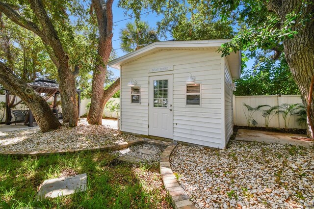 view of outdoor structure featuring an outbuilding, a fenced backyard, and a gazebo
