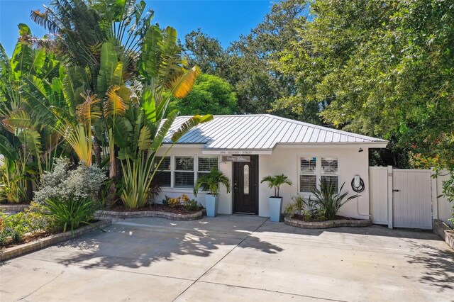 view of front facade featuring a gate, stucco siding, and metal roof
