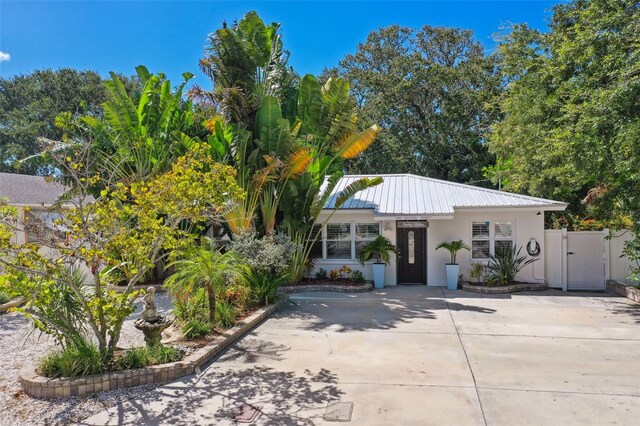 view of front of property with stucco siding, a gate, and metal roof