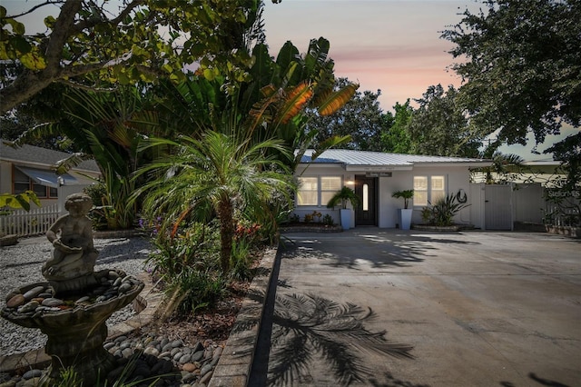 view of front facade featuring metal roof, fence, and stucco siding