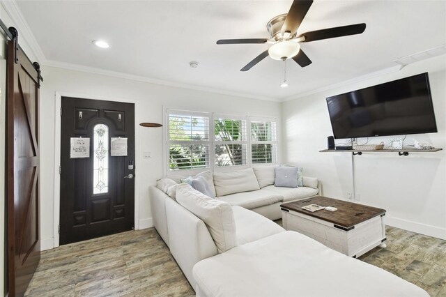 living room with a barn door, ceiling fan, wood finished floors, crown molding, and recessed lighting