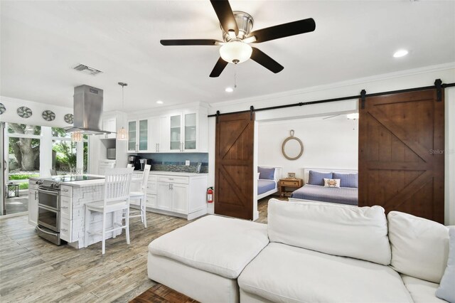 living room featuring ornamental molding, recessed lighting, visible vents, and a barn door